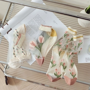 Detailed view of sheer tulip mesh socks on a glass cart with lifestyle props