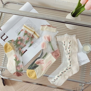 Detail of sheer tulip embroidered socks with reinforced cotton heel on glass shelf