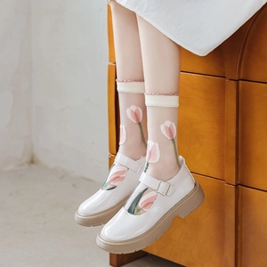 Detail of sheer mesh socks with pink tulip embroidery paired with white Mary Jane shoes