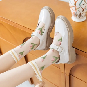 Detailed view of sheer tulip embroidered socks paired with white platform Mary Jane shoes