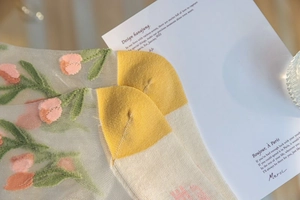 Detail of sheer mesh socks with pink tulip embroidery and yellow contrast heel