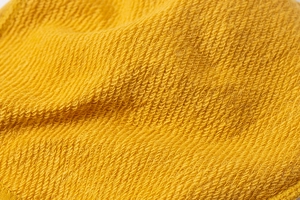 Macro detail of soft bright yellow knitted fabric texture with clear stitching patterns