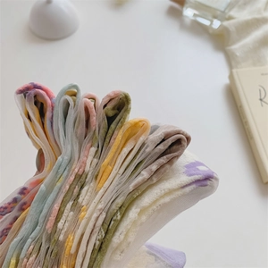 Detailopname van pastelkleurige gebreide sokken met bloemen op een wit vlak