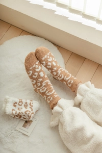 Detailed texture of thick leopard print coral fleece sleeping socks on white plush rug