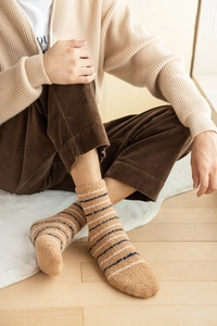 Detail of warm striped coral fleece socks worn with corduroy pants on wooden floor