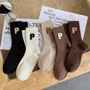 Détail de chaussettes en coton côtelé avec cinq tons terreux et broderie de la lettre P