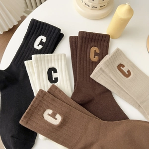 Gros plan de chaussettes en coton côtelé avec broderie lettre C aux tons de terre
