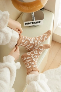 Close-up of warm coral fleece socks with leopard print design and soft plush texture
