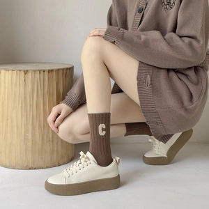 Baskets à plateforme blanc cassé et chaussettes mi-mollet en maille marron brodées d'un C