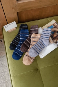 Detailed close-up of five pairs of striped coral fleece thermal socks in a home setting