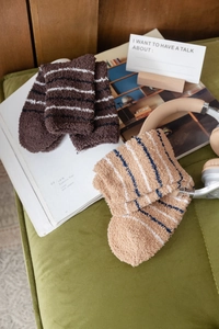 Detail of warm striped coral fleece socks on a cozy sofa showing fluffy soft texture