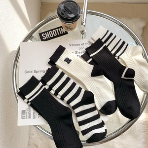 Flat lay of four minimalist black and white crew socks with R letter embroidery