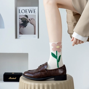Detail of knit cotton socks with pink floral patterns and green stems in loafers