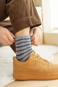 Detailed texture of thick striped coral fleece warm socks worn in a cozy home setting