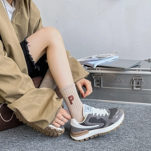 Détail de chaussettes en coton café clair avec broderie P et baskets de style rétro