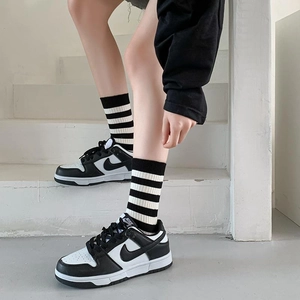 Detail of embroidered striped cotton socks styled with black and white leather sneakers