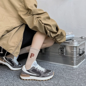 Détail des chaussettes en coton kaki avec broderie lettre P rouge et baskets rétro