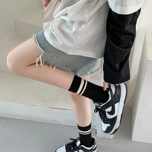 Detail of striped cotton mid-calf socks paired with black and white leather sneakers