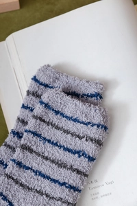 Macro detail of thick striped coral fleece socks with fluffy texture on white book