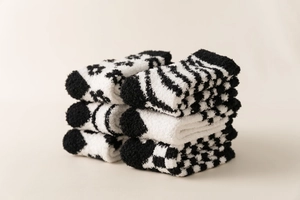 Detailed close-up of six pairs of plush coral fleece socks with black and white patterns