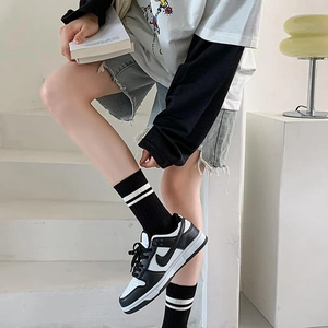 Classic black and white low-top sneakers shown in a stylish urban streetwear setting