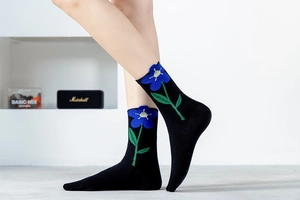 Detailed view of black cotton socks featuring blue floral embroidery and wavy cuffs