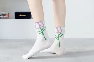 Detail of white cotton sock with purple floral embroidery beside a Marshall speaker