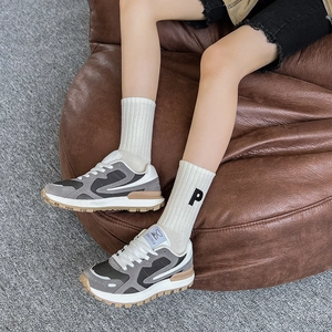 Gros plan de baskets rétro grises avec semelles gomme et chaussettes à broderie lettre P