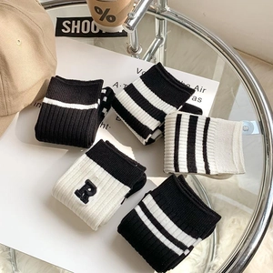Detail view of cotton mid-calf socks with striped patterns and R letter embroidery