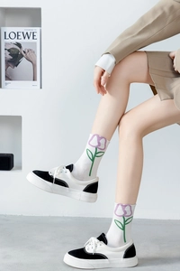Detail view of white cotton socks with purple tulip embroidery and canvas sneakers