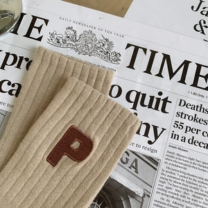 Détail d'une chaussette en coton côtelé kaki avec broderie de la lettre P sur le bord