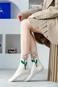 Detail of crew socks in cream white with large floral embroidery worn by a model