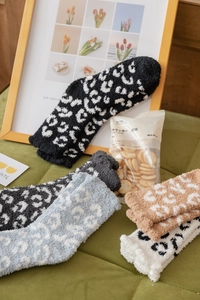 Detailed close-up of thick leopard print coral fleece socks in cozy home setting