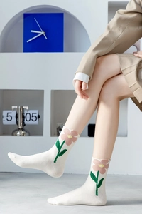 Detail of white cotton socks with pink floral and green leaf knit embroidery pattern