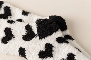 Detailed macro view of soft fuzzy sherpa fabric with black heart spots on white socks