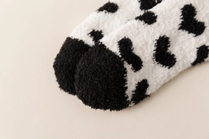 Detailed macro view of the soft coral fleece toe with black heart pattern on warm white socks