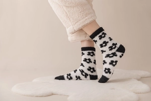 Detail of coral fleece socks with black and white floral pattern on a cozy carpet