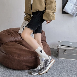 Détail de chaussettes en coton blanc brodées 'P' et chaussures décontractées bicolores