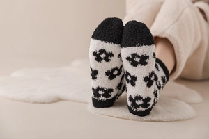 Close-up of black and white coral fleece socks featuring abstract floral patterns on soft rug