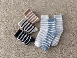 Close-up of thick striped coral fleece socks in various colors on soft textured fabric