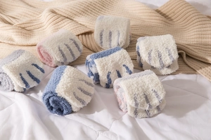 Close-up of soft coral fleece winter socks with cute cartoon cat paw stripe patterns