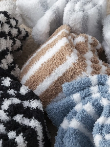 Close-up of thick fuzzy coral fleece socks with striped and polka dot patterns