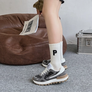 Gros plan de baskets compensées gris-blanc avec chaussettes brodées d'un P