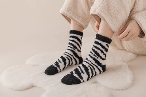 Detail of zebra striped coral fleece socks worn on feet for warm indoor comfort