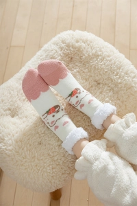 Close-up of thick coral fleece socks with cute strawberry and cat patterns for winter