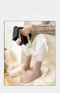 Thick pink wool socks with cable knit texture paired with white plush slippers for winter