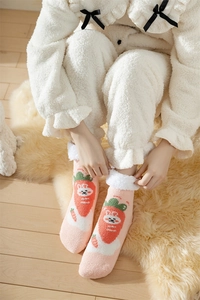 Close-up of pink coral fleece socks with cute rabbit patterns and plush white trim