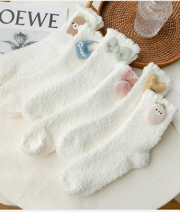 Detail of five pairs of white fuzzy coral fleece socks with cute cartoon 3D animal patches