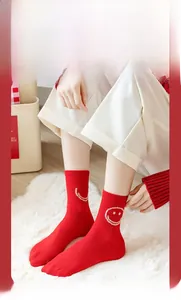Detail of red crew socks with white smile face pattern on white plush carpet
