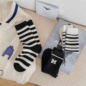 Detail of striped terry socks and black mid-calf socks with white M letter embroidery